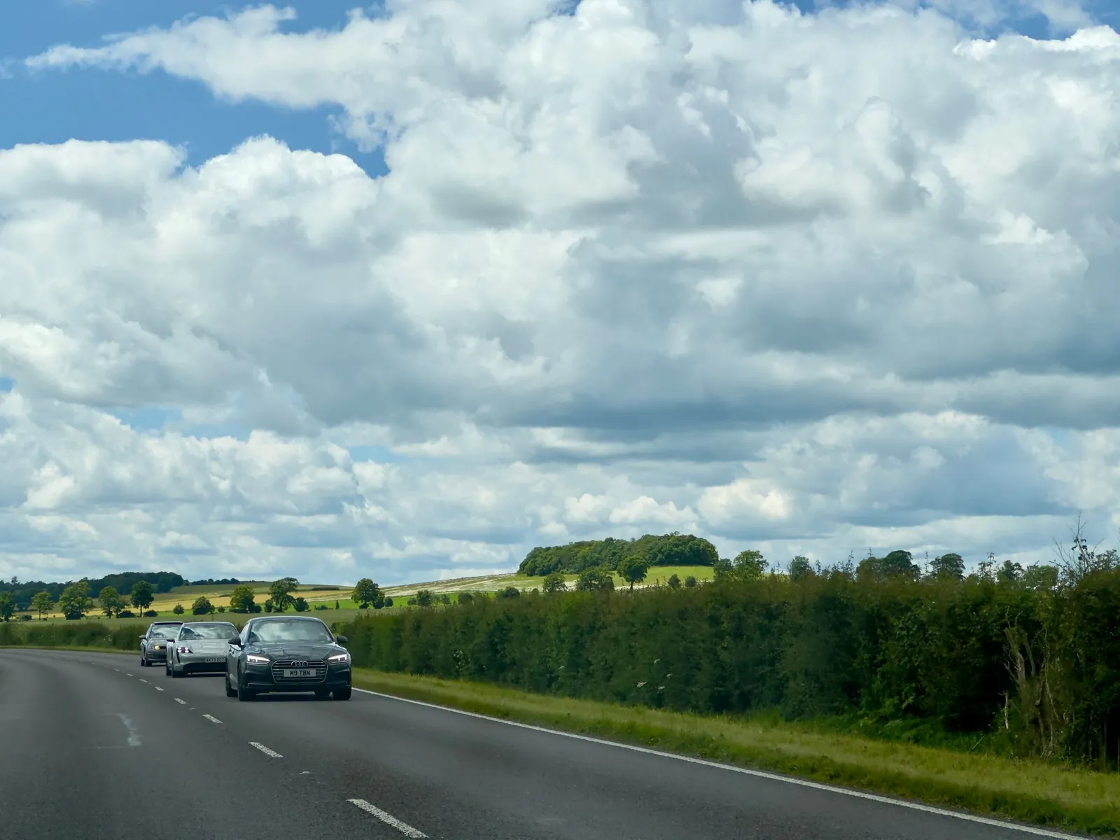 Voitures sur une route de campagne, au loin, sous un grand ciel